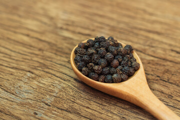 Close Up of peppercorn in wooden spoon on old wooden table.