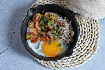 Pan-fried eggs in a black pan on a gray background.