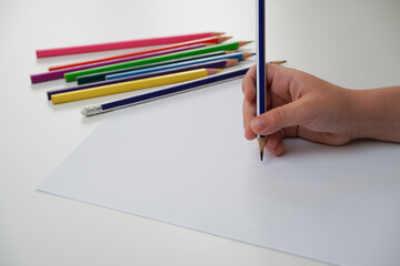 Kid hands with pencil writing in a white empty paper, child drawing, Education and children...