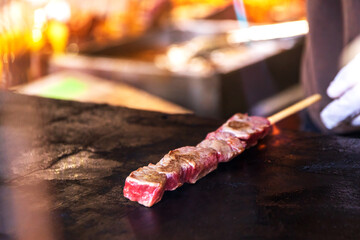 Wagyu beef skewer on grill at street stall in Arashiyama, Kyoto, Japan.