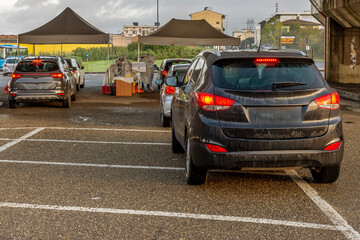 Two rows of cars in queue, waiting for the test swab of the possible covid-19 coronavirus infection in a drive in with two gazebos, Empoli, Florence, Italy