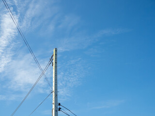 Electric poles and wires in a bright blue sky background.