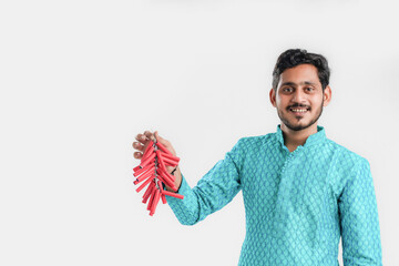 Diwali festival concept, Young Indian man in ethnic wear and holding Red firecrackers string in hand