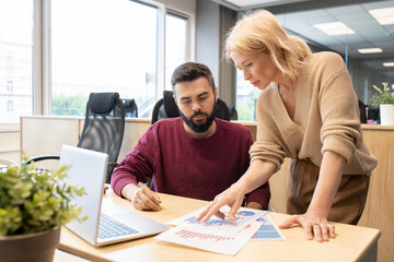 Blond mature businesswoman discussing diagrams and charts with male colleague