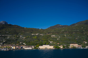 Fototapeta premium Panoramic view of the sights on Lake Garda Italy. Aerial view of architecture on Lake Garda. Ancient villa on Lake Garda in the background Alps and blue sky.