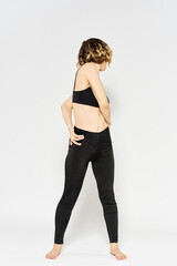 Obraz premium sporty woman in black jeans and a t-shirt doing exercises in a bright room