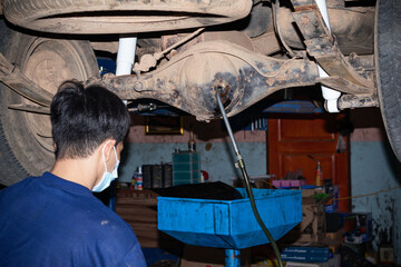 Fototapeta na wymiar Mechanician changing car wheel in auto repair shop wearing a mask, coronavirus concept