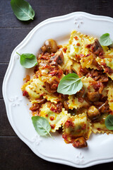 Ravioli with mushrooms and fresh basil. Dark wooden background. Top view.	