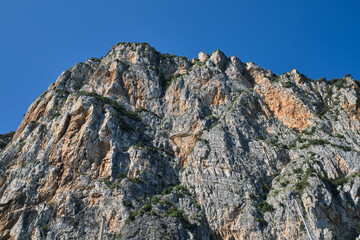 Alps top on blue sky. Rough rocky stones. Gray rocks at high altitude. Red stones on a blue background. The tops of the yellow peaks of the rocks.