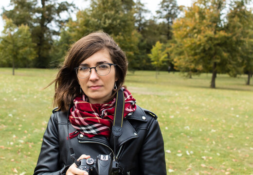 Young female photographer reviewing the photos taken with her camera and wearing a red scarf and a black leather jacket