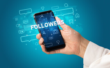 Female hand typing on smartphone with FOLLOWERS inscription, social media concept