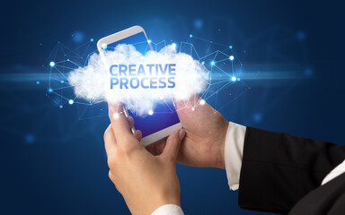 Female hand touching smartphone with CREATIVE PROCESS inscription, cloud business concept