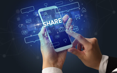 Female hand typing on smartphone with SHARE inscription, social media concept