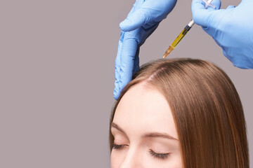 Doctor hands in protective medical gloves. Hair injection. Pretty young woman. Face anti age...