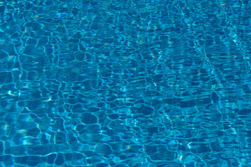 Blue water in the pool with solar reflections. Swimming pool. Water reflex texture from the pool