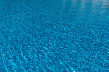 Blue water in the pool with solar reflections. Swimming pool. Water reflex texture from the pool