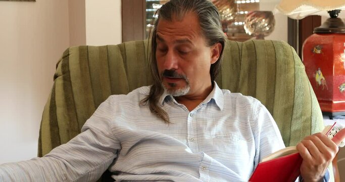 Middle aged man reading a novel at home