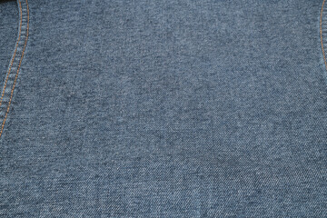 Blue denim jeans texture background with seam and orange thread stitches.