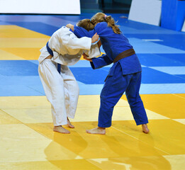 Two Girls judoka in kimono compete on the tatami 