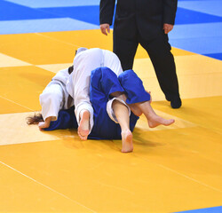 Two Girls judoka in kimono compete on the tatami 