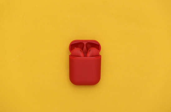Red wireless headphones with charging case on a yellow background. Top view