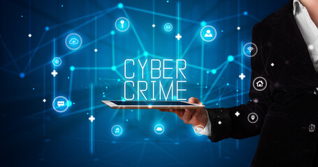 Young business person working on tablet and shows the digital sign: CYBER CRIME