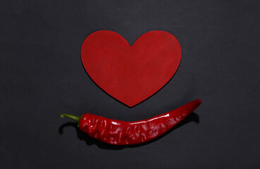 Chilli pepper and heart on black background. Love concept. Top view