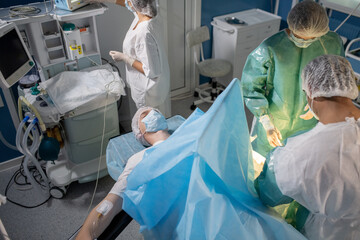 Patient lying on operation table while professional surgeons bending over him