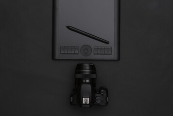 Graphic tablet with pen, camera on black background. Top view