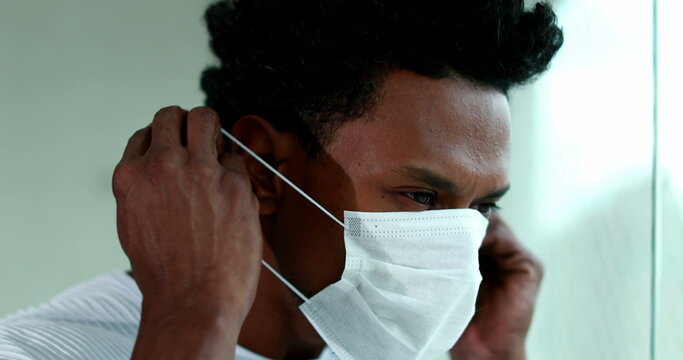 African american man putting covid mask, black person puts on virus prevention mask
