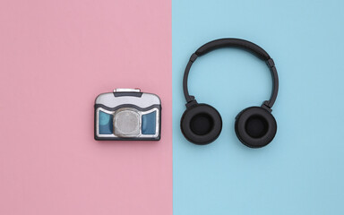 Mini audio cassette player with stereo headphones on a blue pink background. Top view