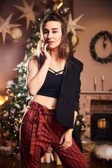 A young beautiful woman in an evening suit at a New Year's party or Christmas party stands and looks into the camera