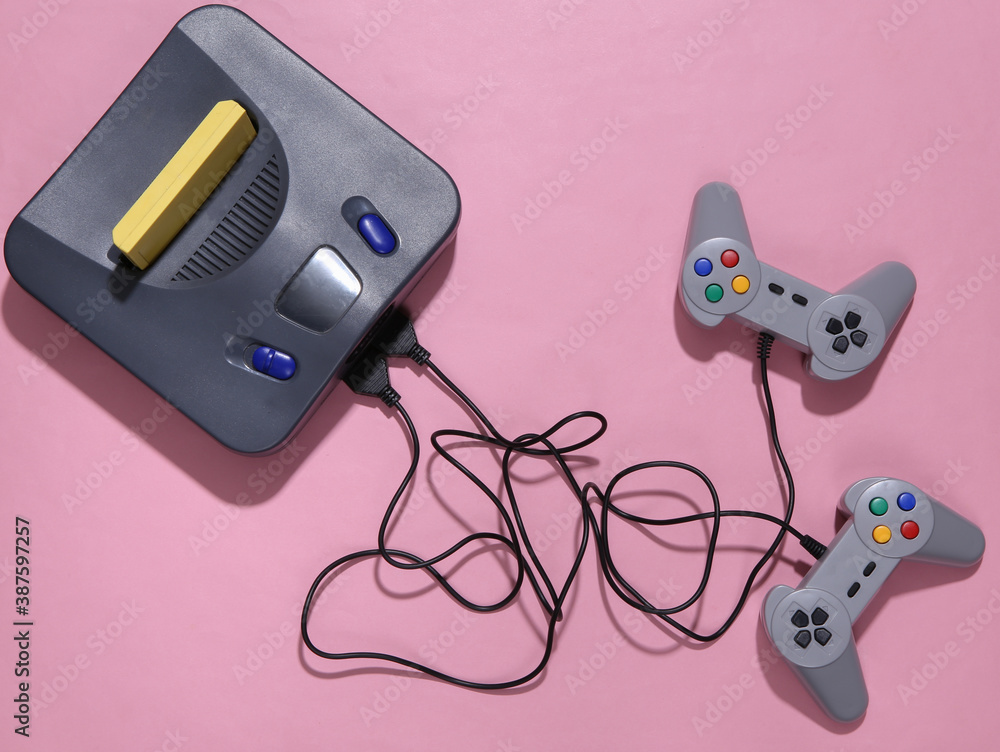 Poster retro video game console with joysticks on pink background. top view