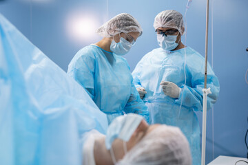 Young female assistant in protective workwear preparing medical instruments