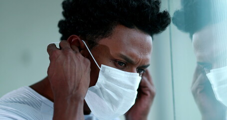 Black man putting on preventive mask during pandemic