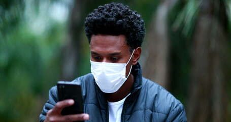 Casual candid black african man looking at smartphone device during pandemic