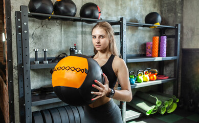 Young Female fitness model exercising with medicine ball at gym. Caucasian woman doing crossfit workout.
