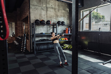 Fit Women training with fitness trx straps in gym. Beautiful lady exercising her muscles with suspension straps.