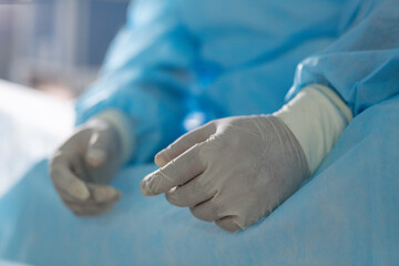 Fototapeta na wymiar Gloved hands of tired professional surgeon sitting in operating room at break