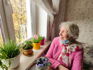 The Covid-19, health, safety and pandemic concept - senior old lonely woman sitting near the window