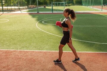 Obraz premium Fit woman with yoga mat at the stadium