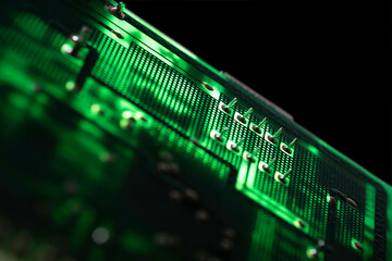 Illuminated green electronic circuit board with many electrical components, isolated on black background