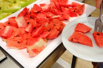 Fruit slices in a plate. A girl holds a plate. Watermelon, melon , oranges . Vitamins, dietary dessert concept.Meals for tourists in hotels and restaurants.