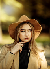 Portrait of an attractive woman with make-up dressed in a coat and felt hat. Walk in the autumn...