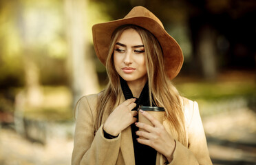 Portrait of an attractive woman with make-up dressed in a coat and felt hat. Walk in the autumn...