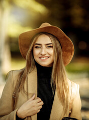 Portrait of an attractive woman with make-up dressed in a coat and felt hat. Walk in the autumn...