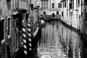 Venice, Italy, December 28, 2018 evocative black and white image of a narrow passage for the 
calle of Venice with a gondola passing in the background