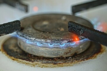 one gray round metal burner with a burning blue flame on the white metal of a gas stove