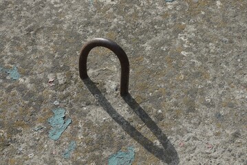 one brown rusty iron loop and ring on a gray concrete slab