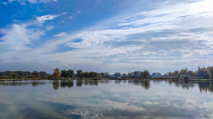 Fototapeta premium Sunny day on the perfect lake. Autumn lake with reflection on the water. Cloudy sky in the sunny day.